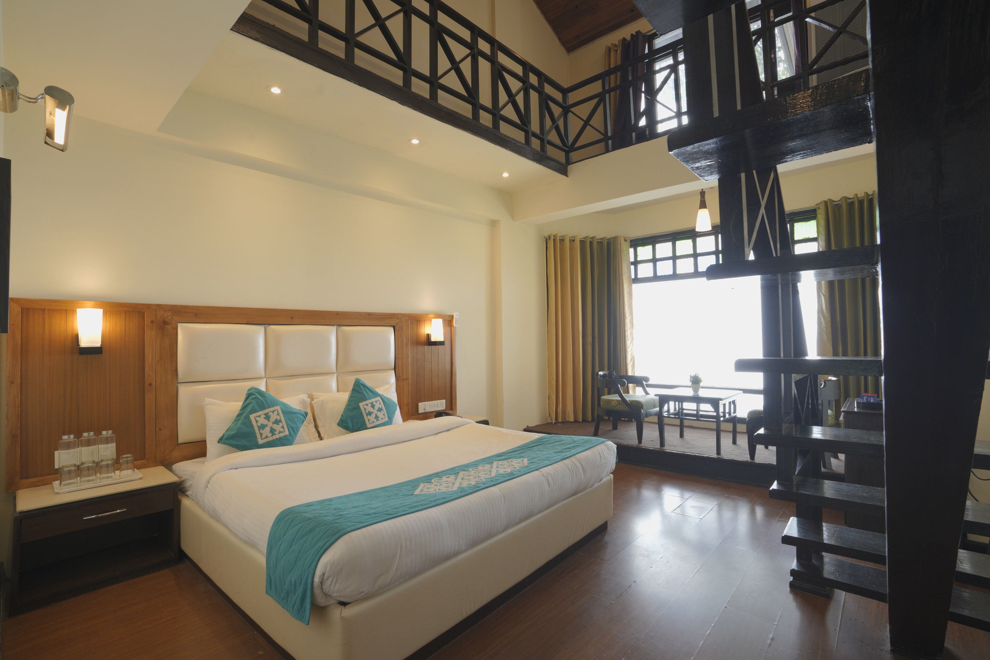 A hotel room with a large bed, wooden headboard, and a balcony with a view.