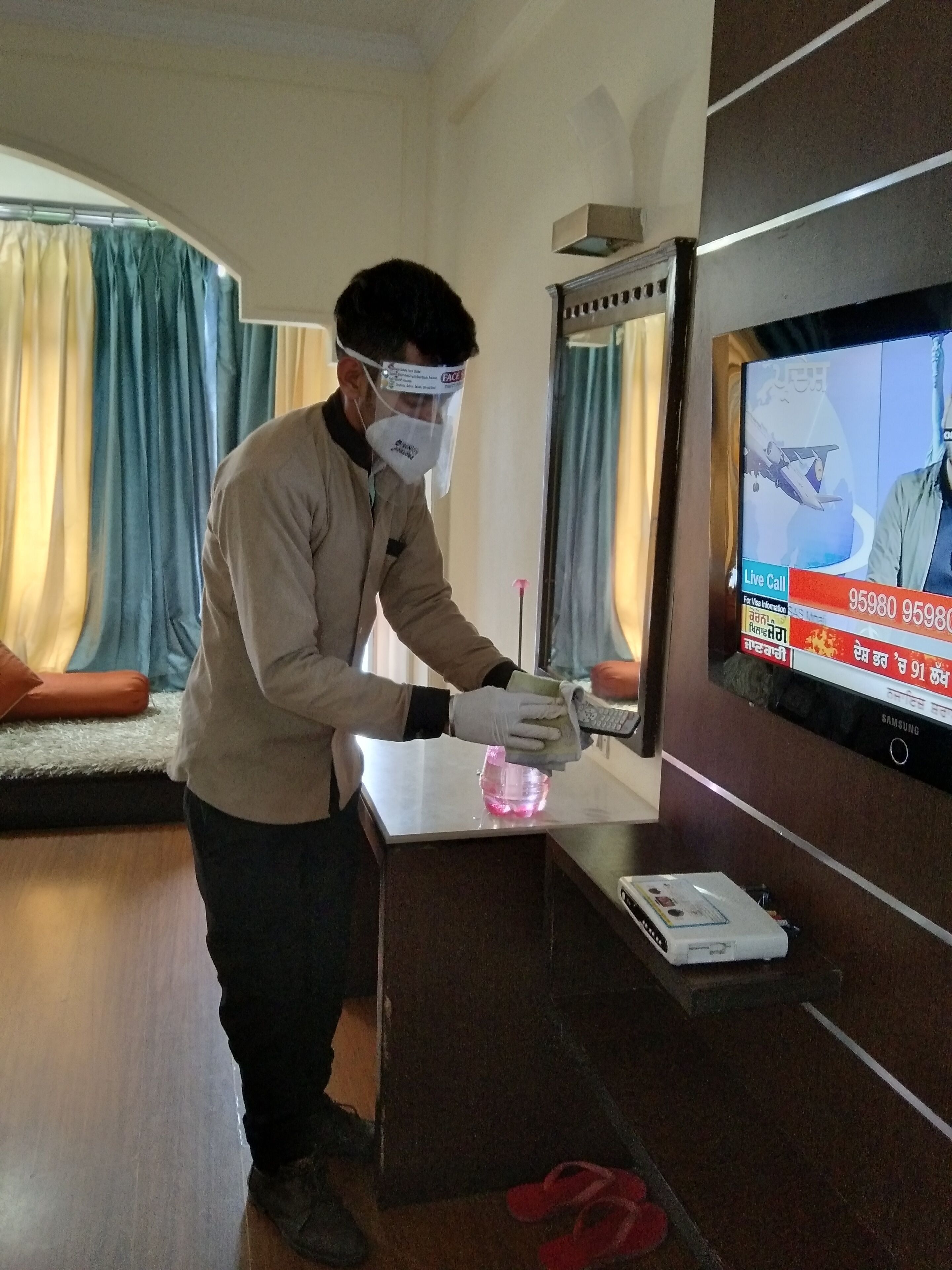 Una persona limpia una superficie de vidrio en una habitación con un televisor que muestra un noticiero.