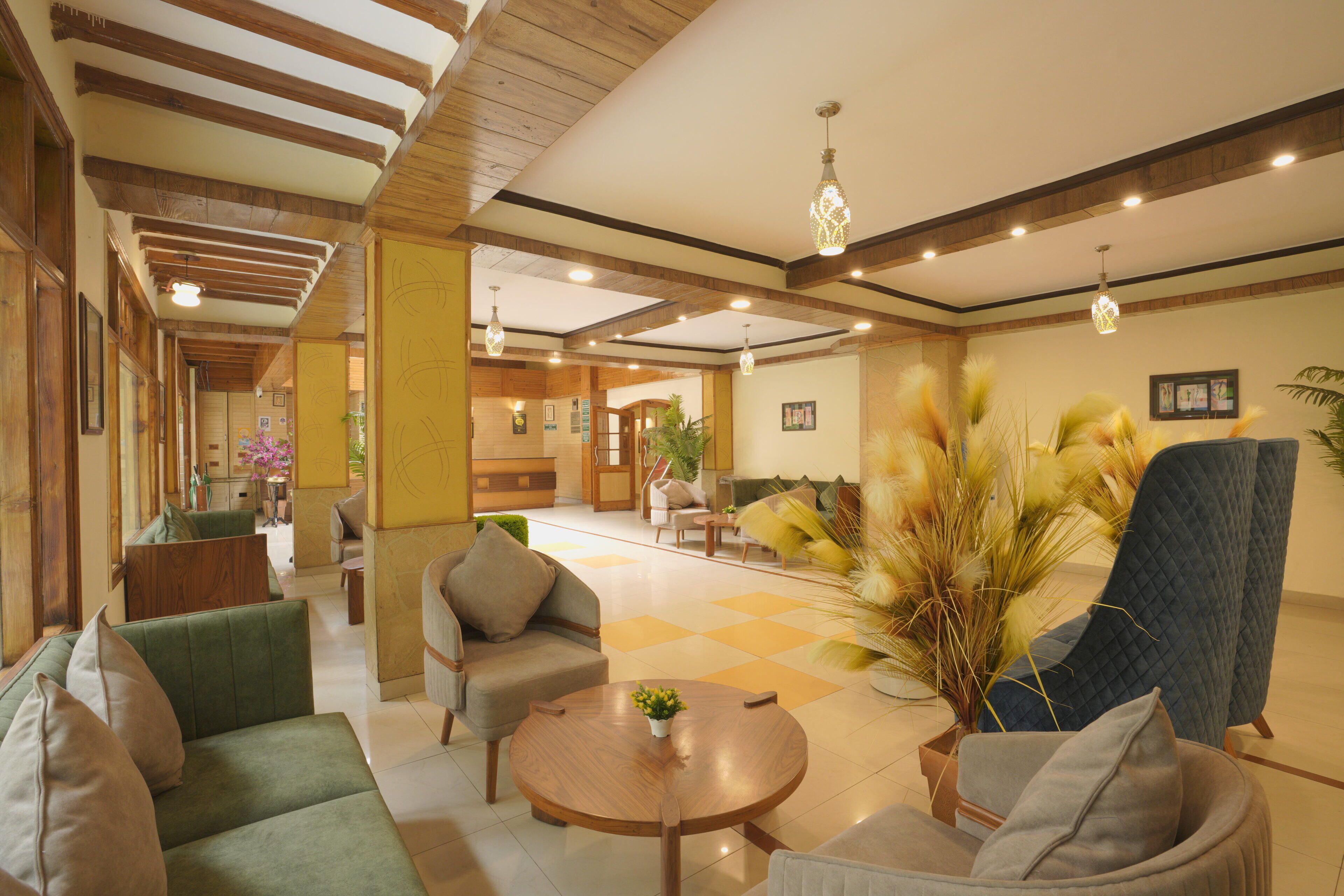 A spacious lobby with a checkered floor, a green sofa, a round wooden table, and a large blue armchair.