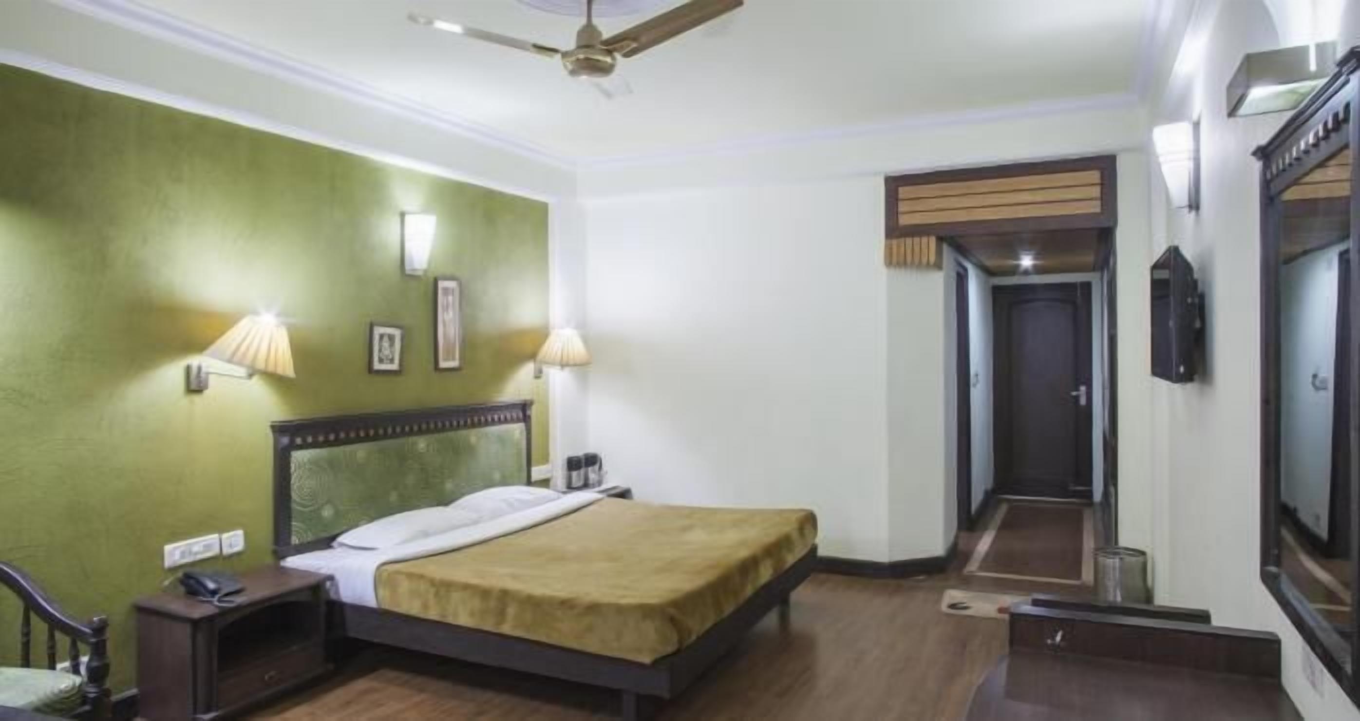 A hotel room with a bed, bedside lamps, a telephone, and a ceiling fan.