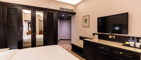 Une chambre d’hôtel équipée d’un lit, d’une télévision, d’un minibar et d’une armoire.