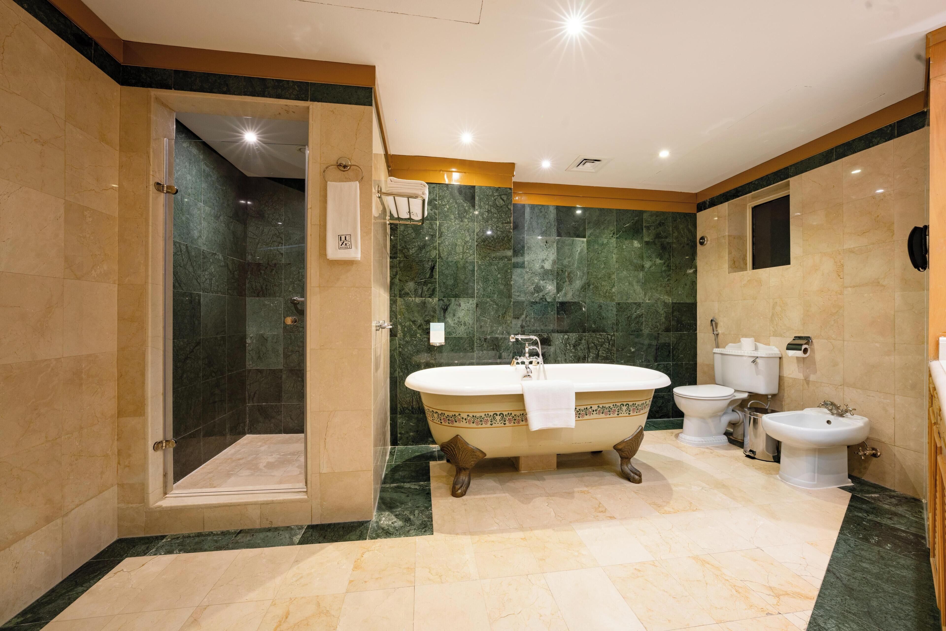 Un baño espacioso con una bañera independiente, cabina de ducha y dos inodoros.