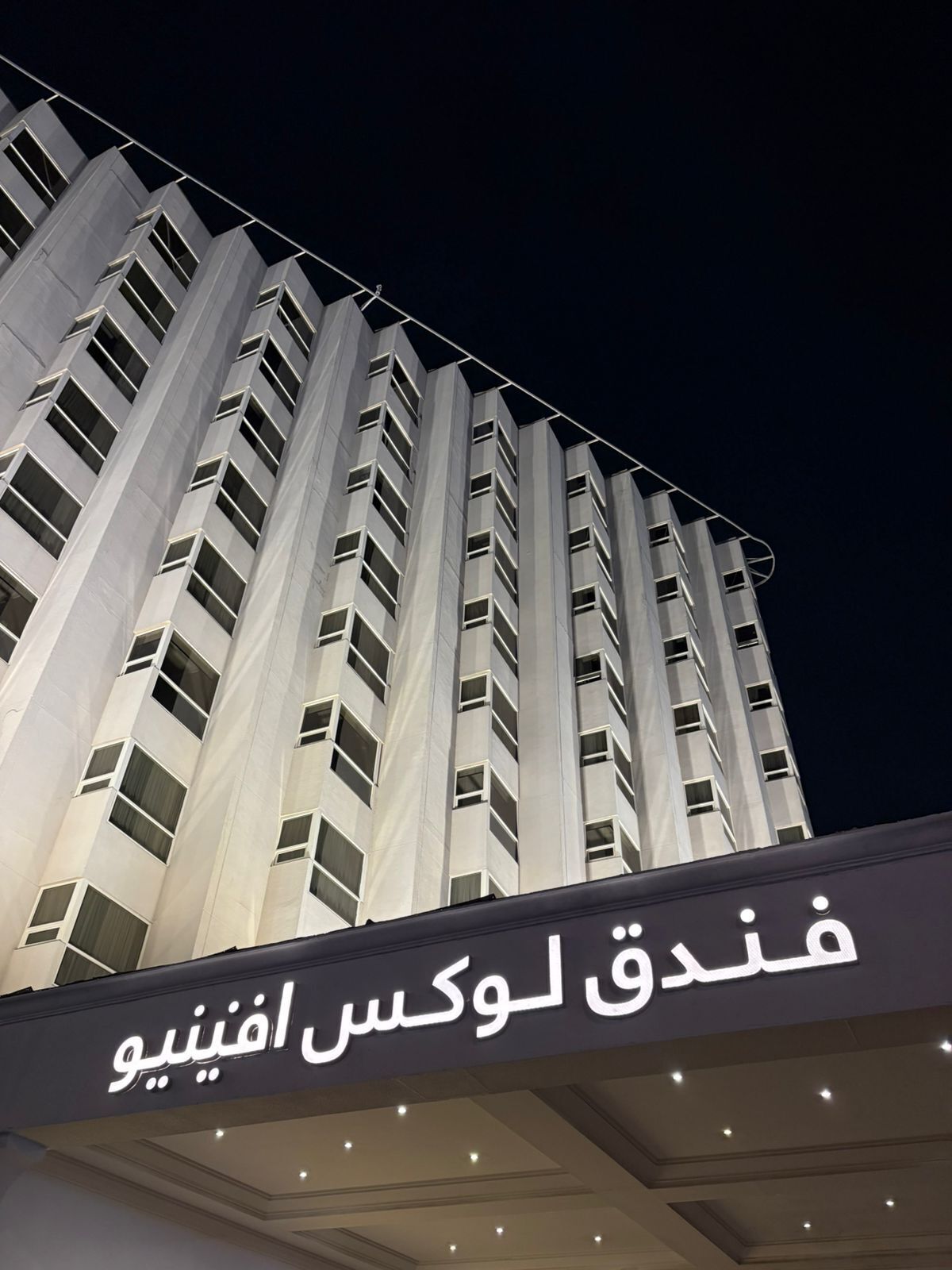 A high-rise building with a sign in Arabic.
