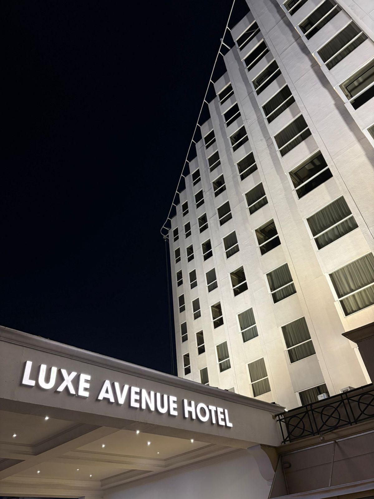 Exterior del Hotel Luxe Avenue con diseño moderno, que destaca una entrada imponente y múltiples ventanales.