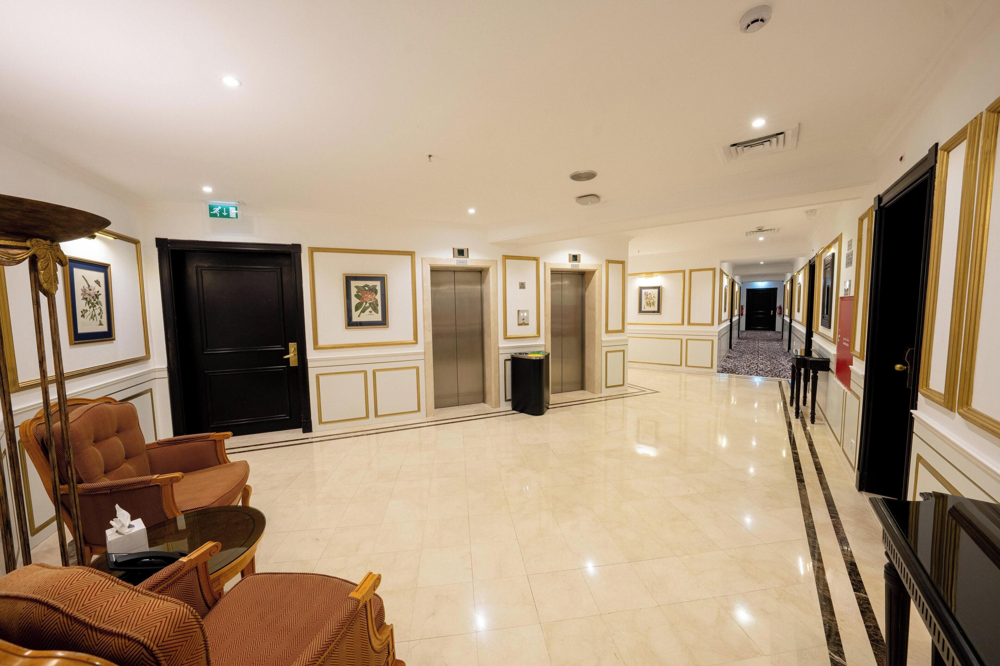 Un vestíbulo de hotel con mostrador de recepción, zona de estar, ascensores y un suelo de mármol pulido.