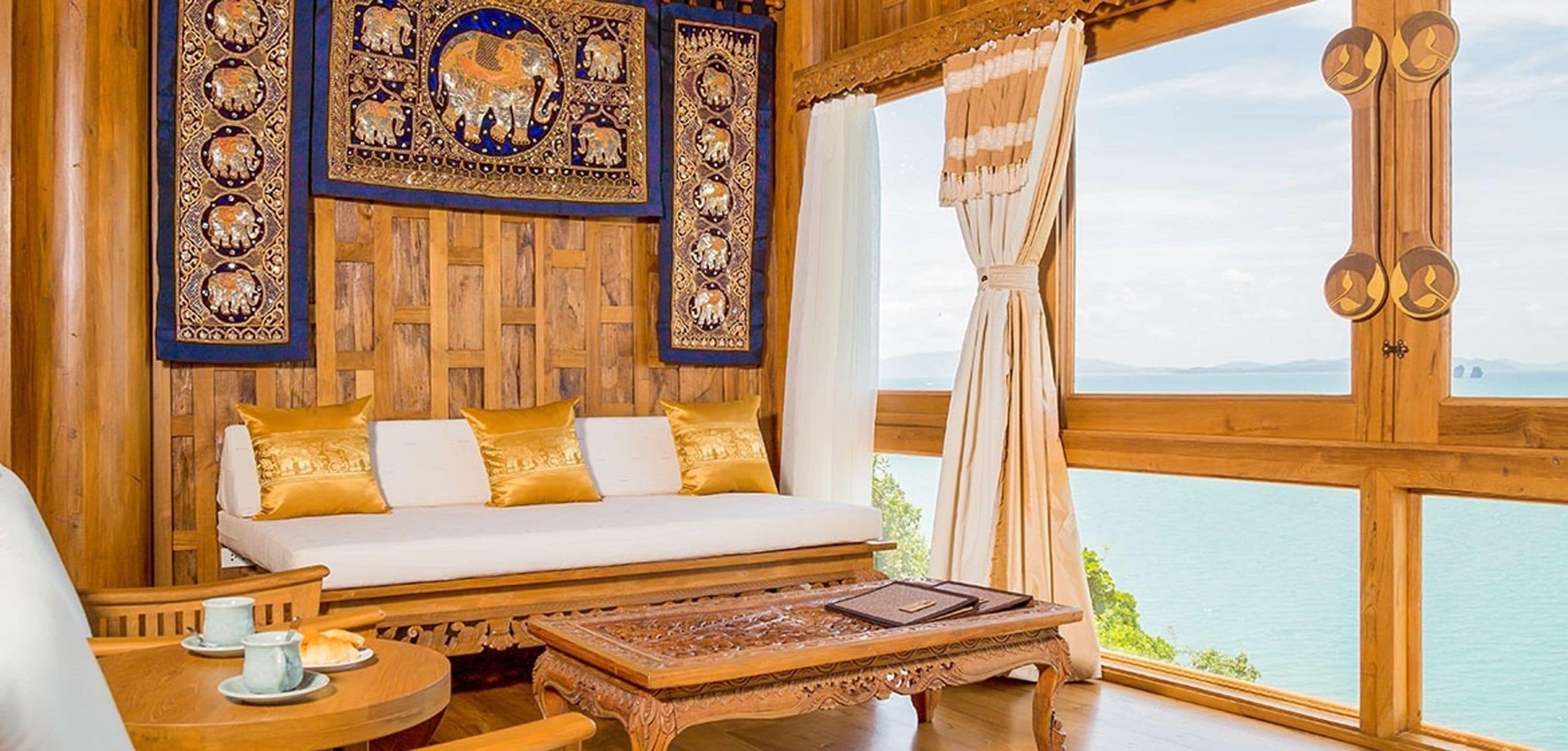 A wooden interior with a sofa, a table, and a view of the sea.