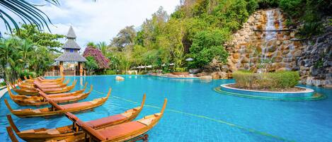 A pool with wooden boats, a gazebo, and lush greenery.