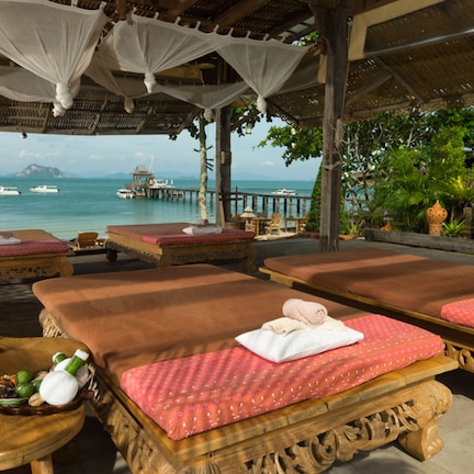 A spa area with massage tables, a wooden bench, and a decorative bowl with flowers.