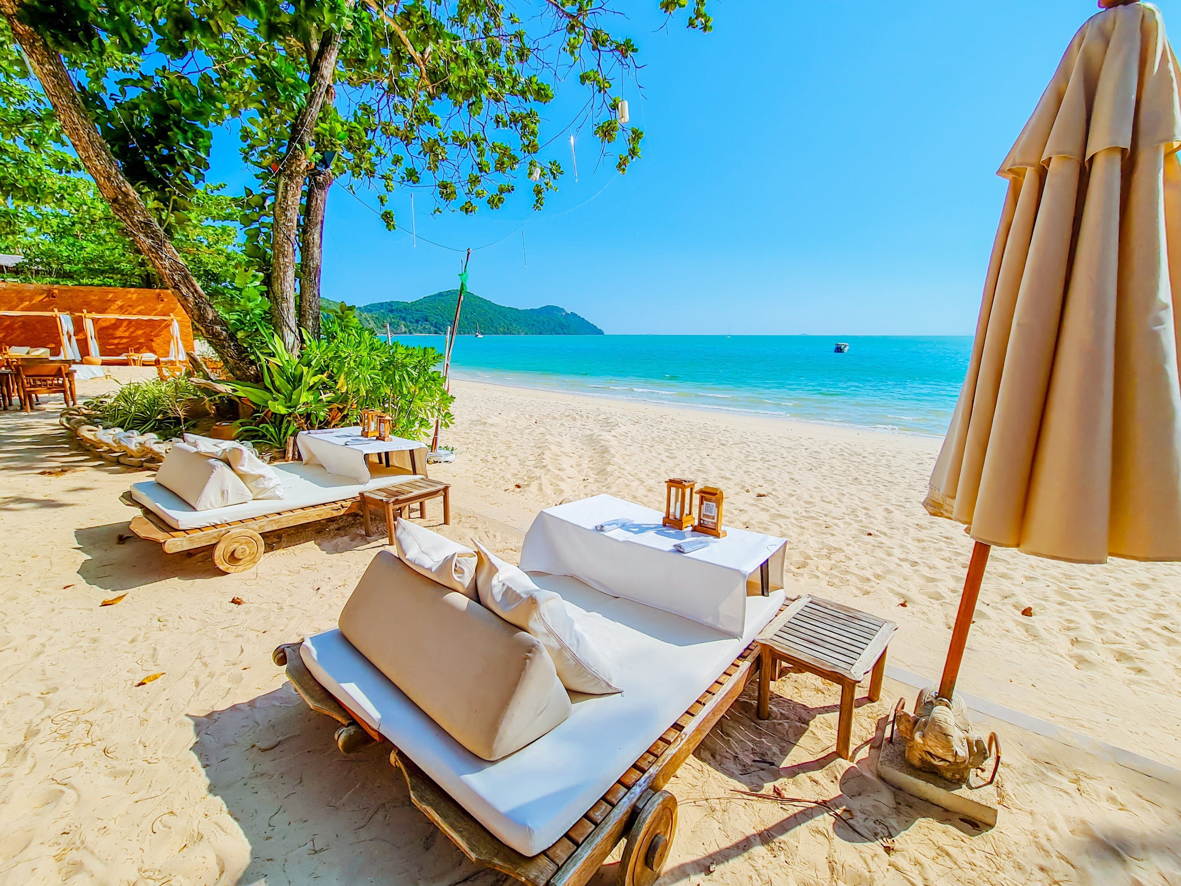 A beachside lounge area with sun loungers, a table, and an umbrella.