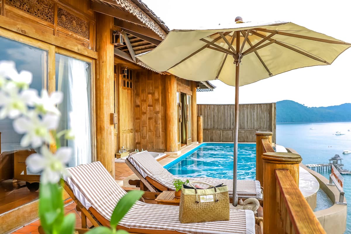 A wooden deck with a pool, lounge chairs, and an umbrella.