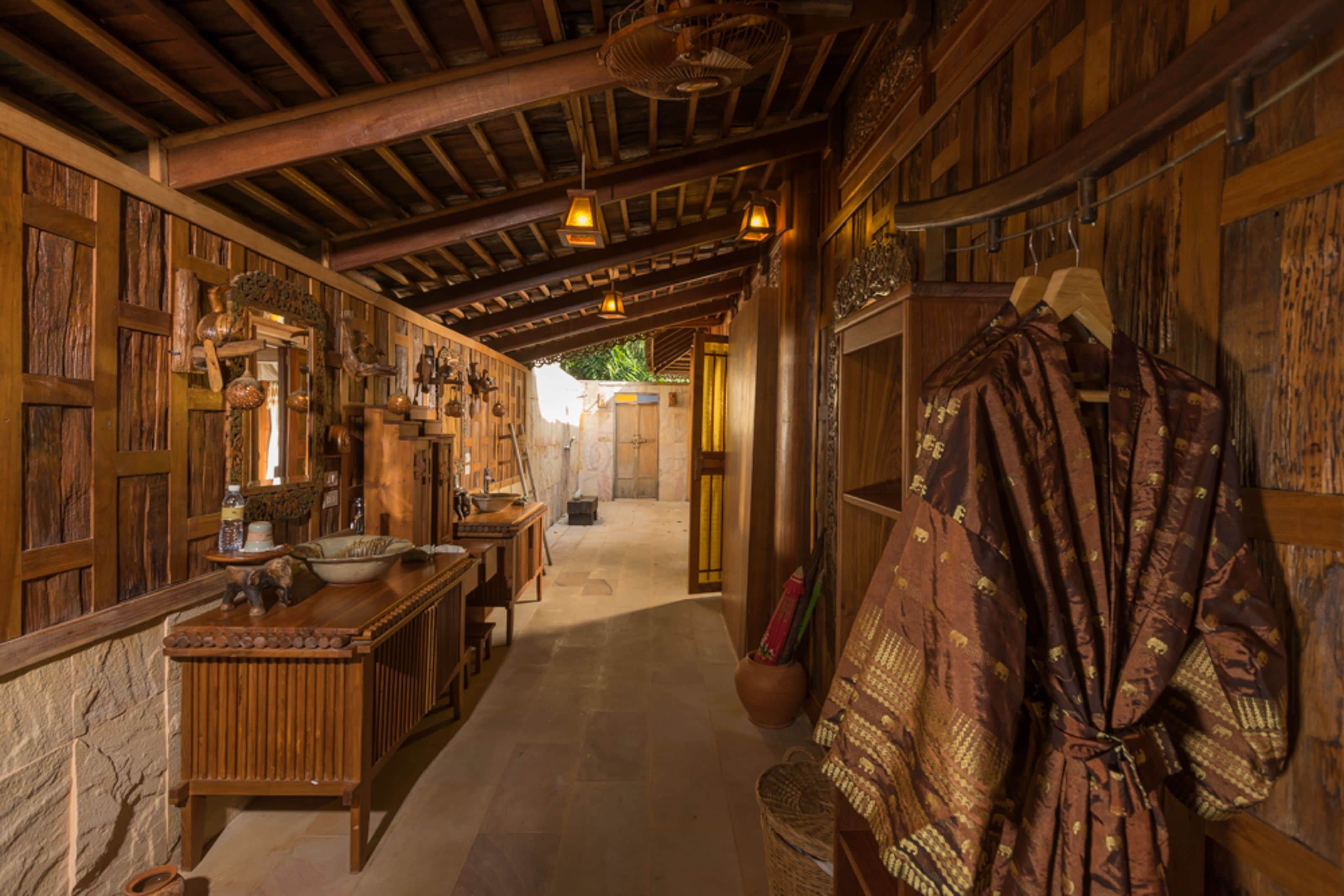 Interior rústico con vigas de madera, un banco central de madera y una prenda colgando.