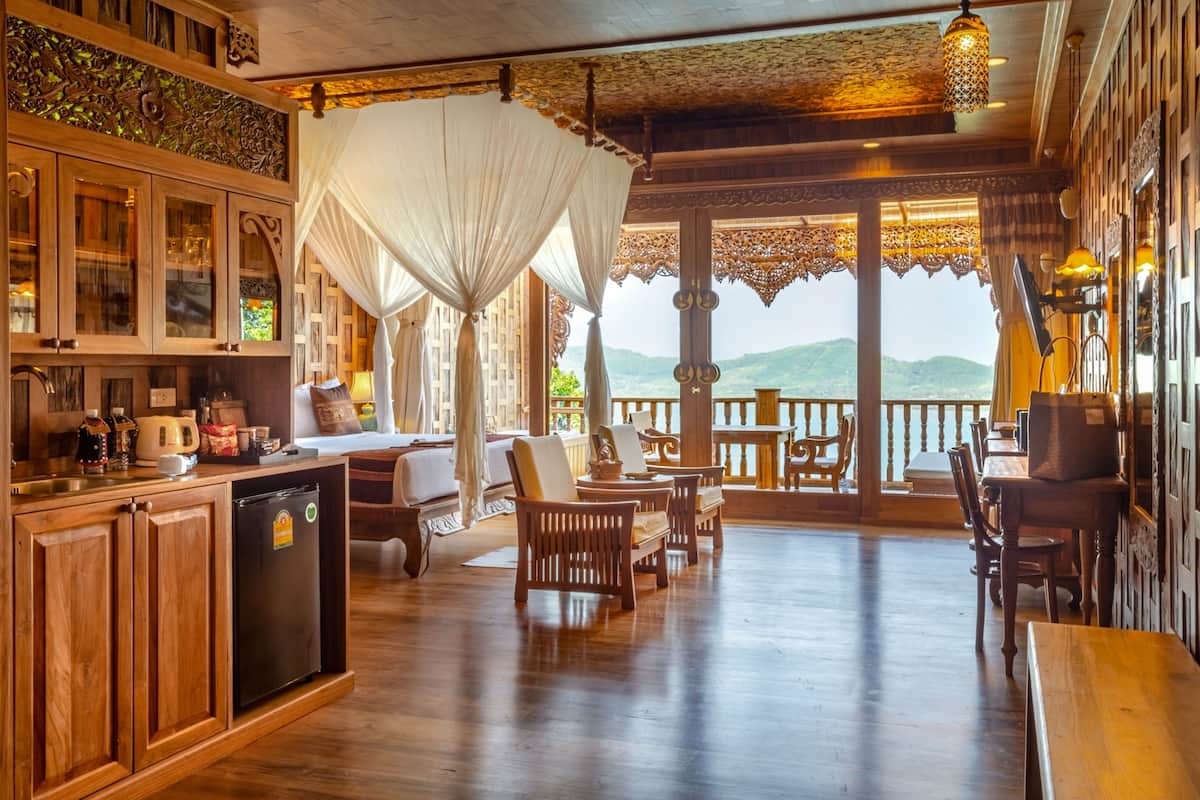 A wooden interior with a dining area, a kitchen with cabinets, and a view through large windows.