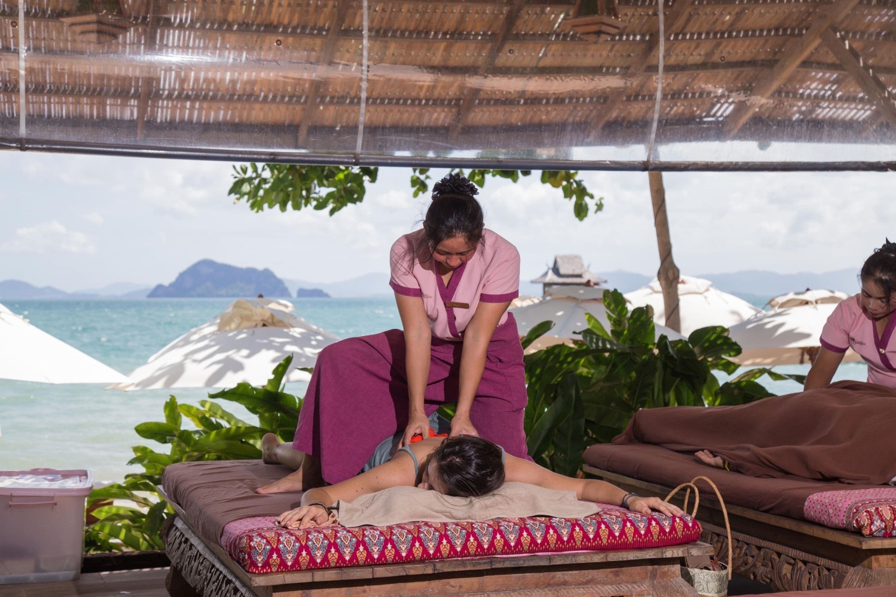 Una sesión de terapia de masajes en un entorno tropical con vistas al océano y a las montañas.