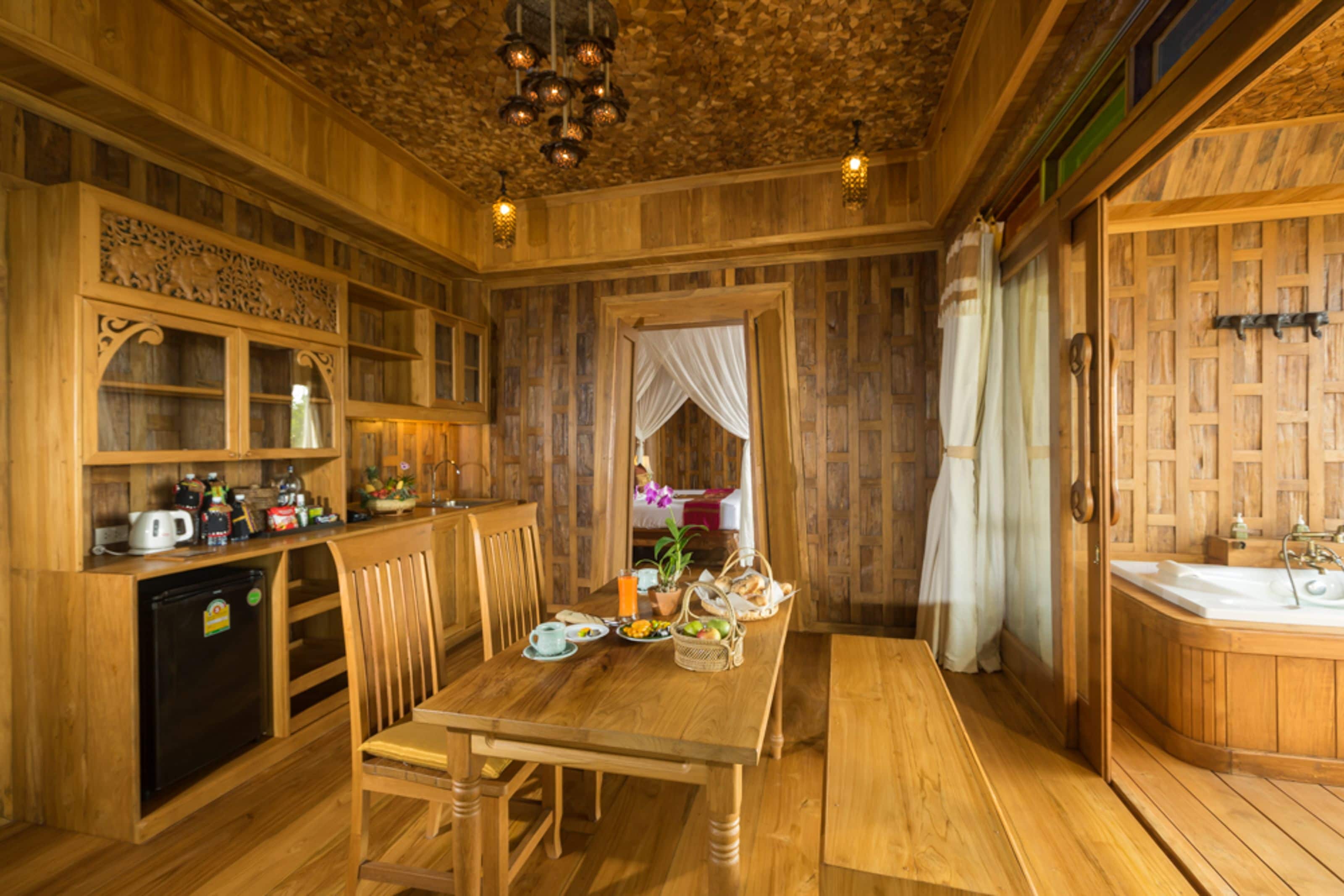Un interior de madera con una mesa de comedor, sillas, un refrigerador, un lavamanos y una bañera.