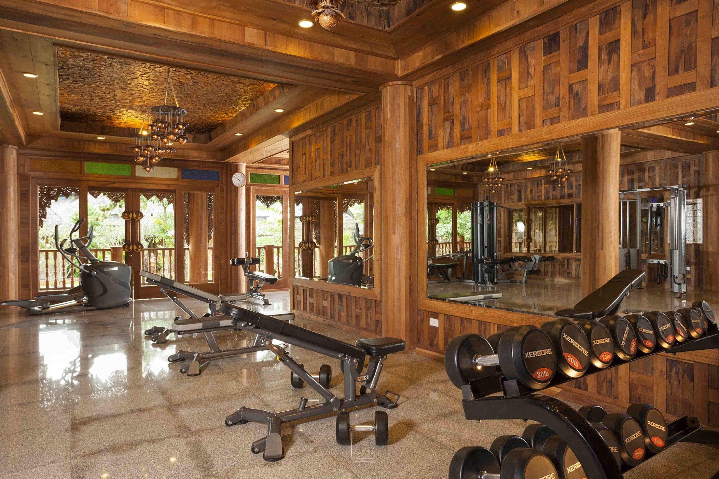 Ein Fitnessstudio mit Holzwänden, Trainingsgeräten und großen Spiegeln.