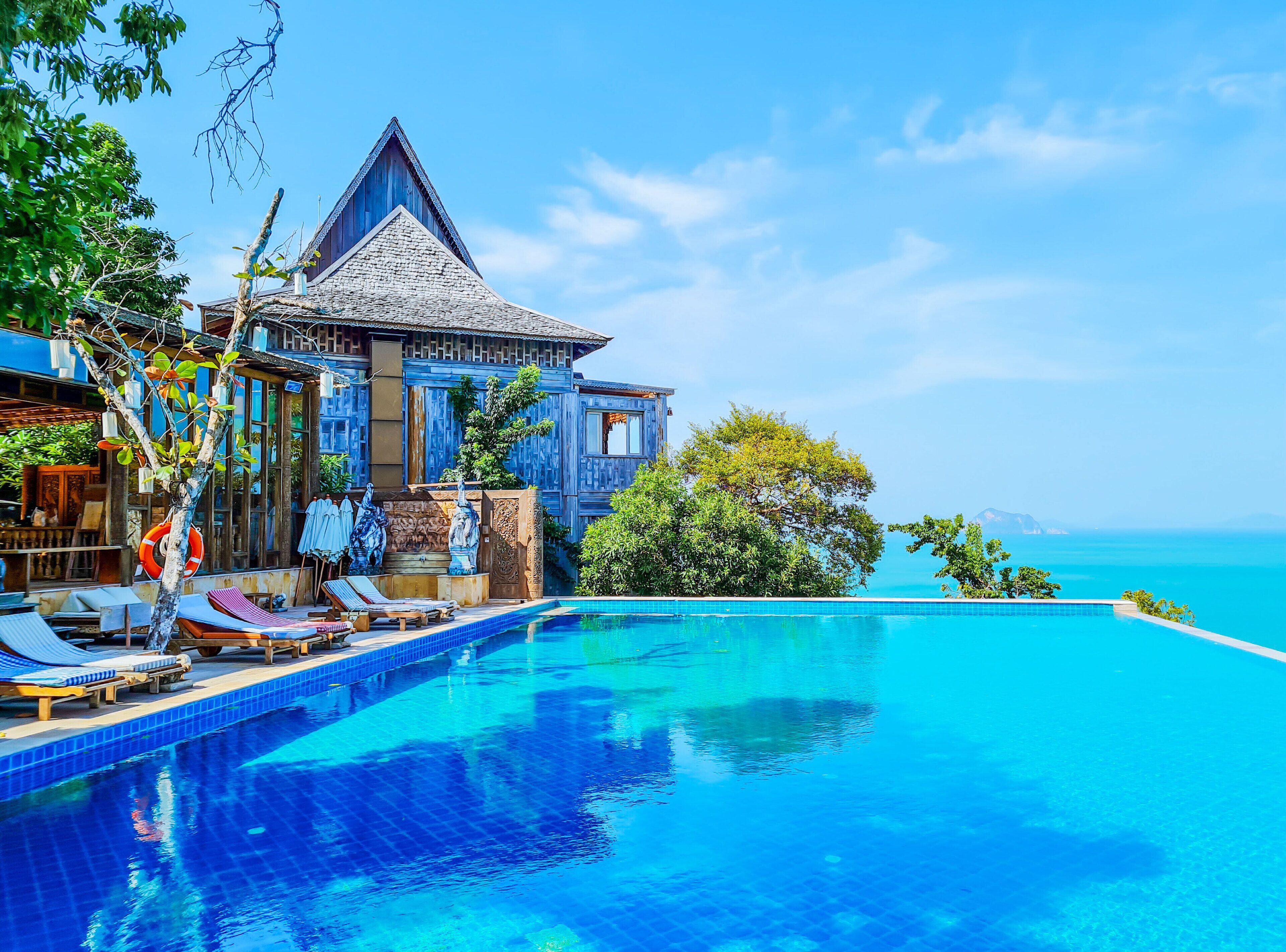 Un resort con piscina, sillones de descanso y vista al océano.