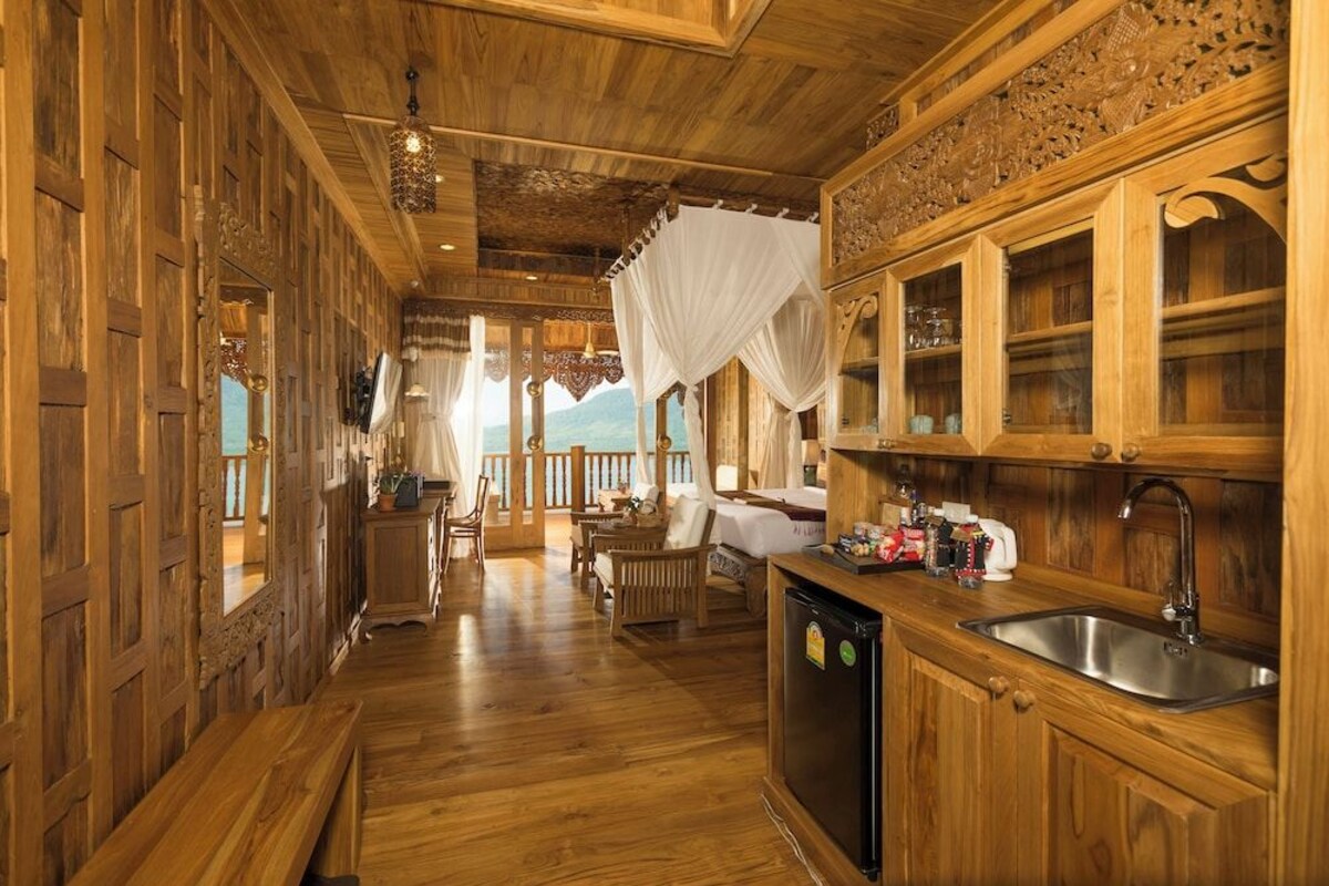 Un interior de madera con una zona de cocina, un comedor y vistas a través de una ventana.