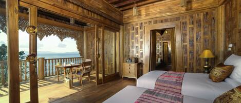 Una habitación de madera con balcón, una cama, un tocador y una mesa con sillas.