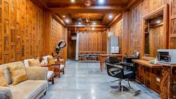 A wooden interior with a sofa, chairs, a desk, and a mirror.