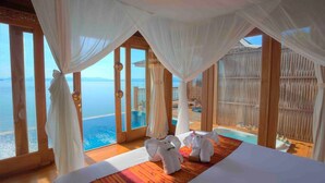 Una habitación lujosa con una cama grande, vista al mar y una piscina.