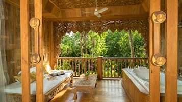 Una terraza de madera con una cama, una mesa con un jarrón y un jacuzzi.