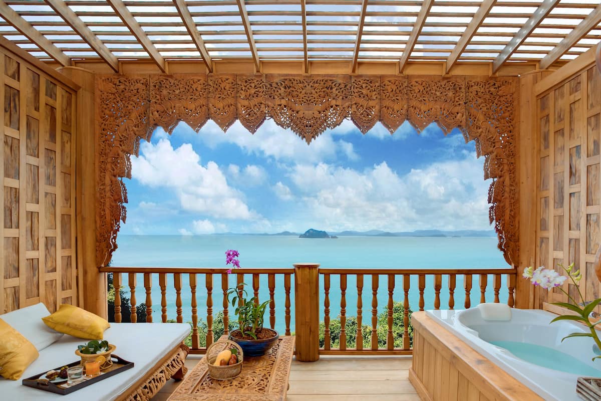 A wooden deck with a sofa, a table with a tray, and a hot tub.