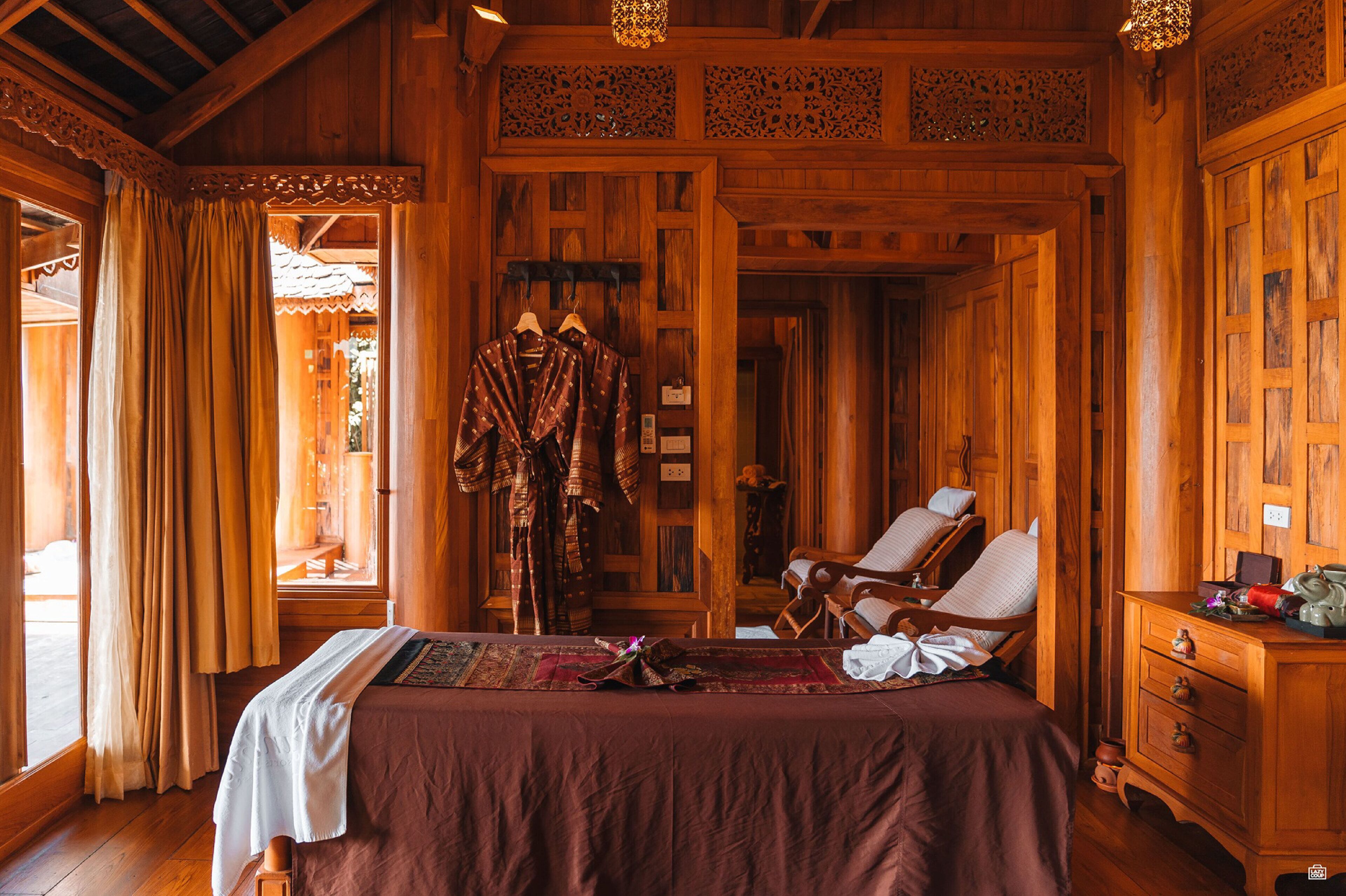 A wooden room with a bed, a chair, and a wardrobe.