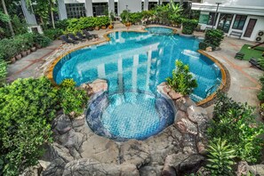 An indoor swimming pool with a circular design, surrounded by lush greenery and rocks. - Mike Garden Resort Hotel (Pattaya)