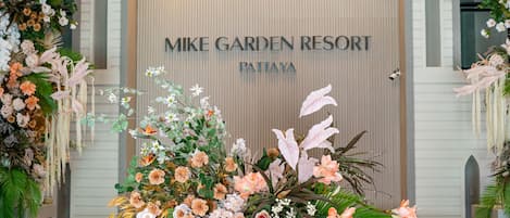 Zona de recepción en Mike Garden Resort Pattiya, con un gran arreglo floral y un mostrador de recepción.