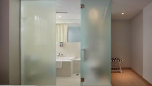 A modern bathroom with a glass partition, a sink, and a shower area. - Ole Tai Sam Un Hotel (Macau)