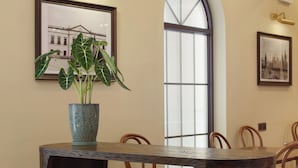 A dining area with a wooden table, chairs, a potted plant, and a large window with a view. - Ole Tai Sam Un Hotel (Macau)