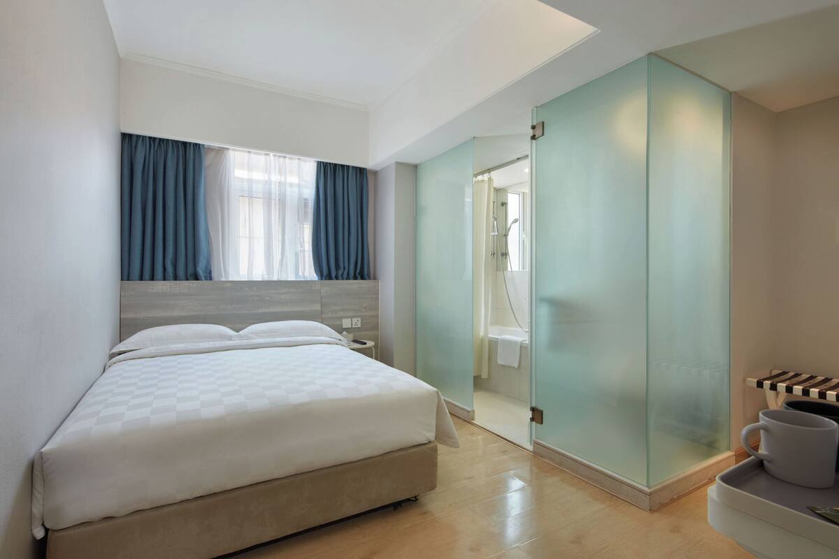 A modern bedroom with a large bed, a bedside table, and a view into the bathroom.