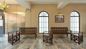 A lobby with two wooden benches, a chandelier, and large windows with arched tops. - Ole Tai Sam Un Hotel (Macau)