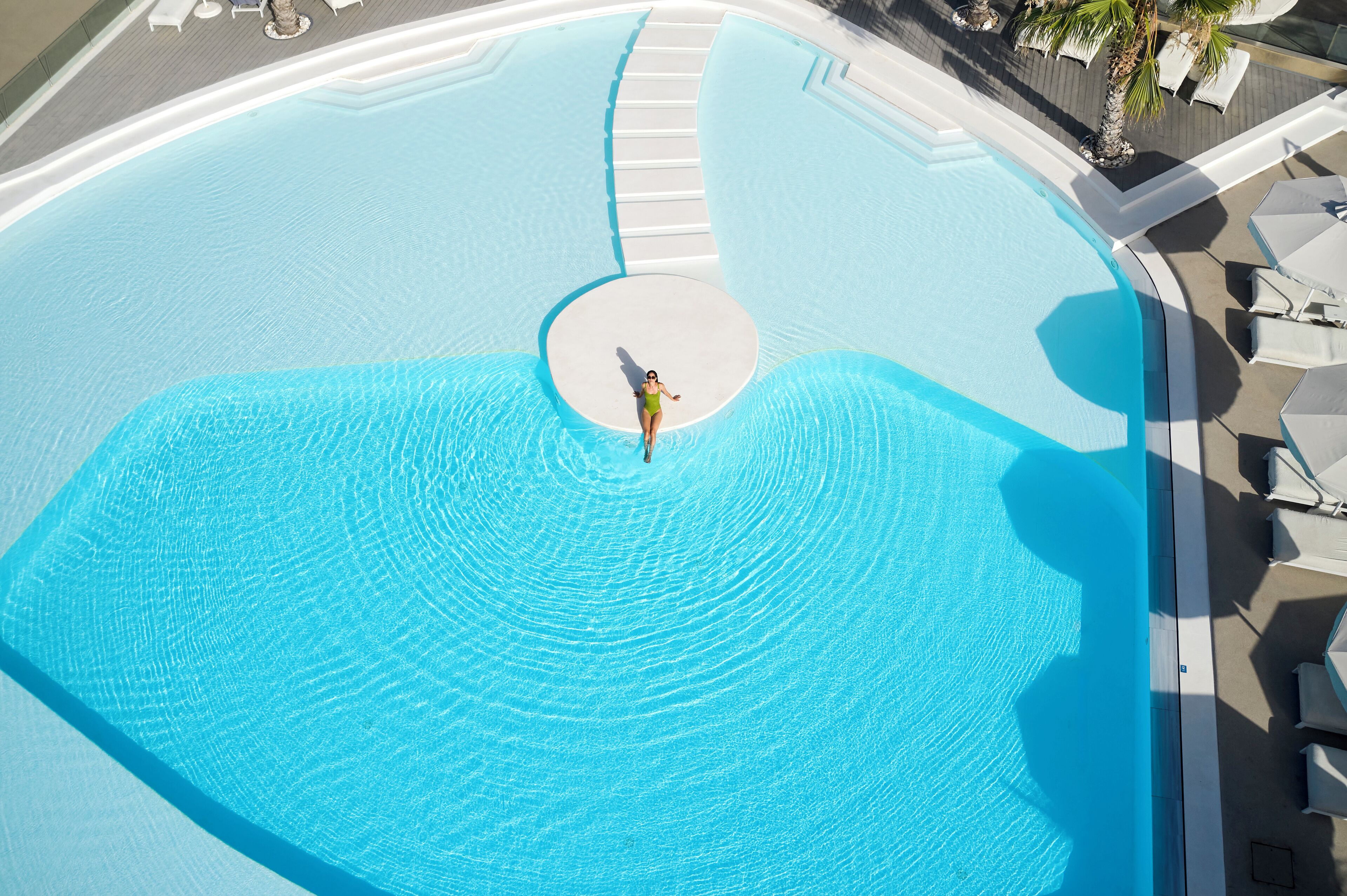 A large, circular swimming pool with a central circular platform and steps leading into the water.