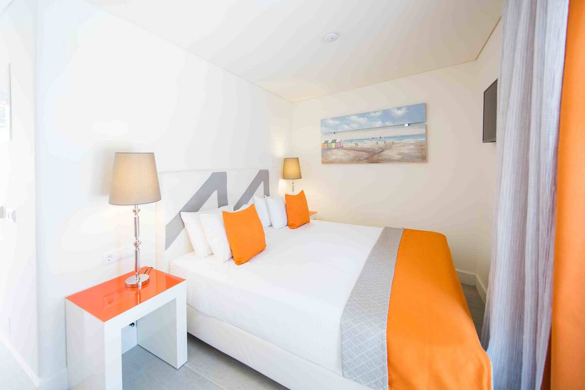 A hotel room with a bed, two bedside tables, and a painting on the wall.