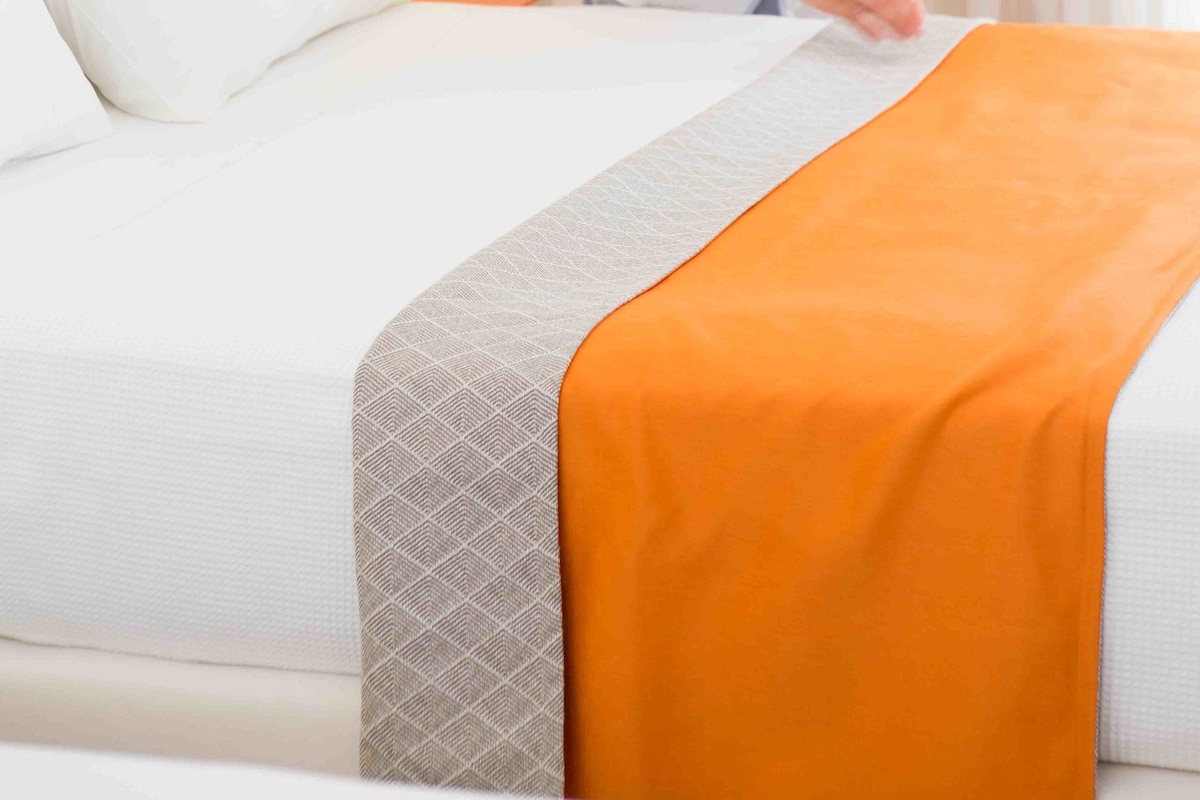 Una habitación de hotel con una cama bien hecha, una lámpara y una ventana con cortinas.