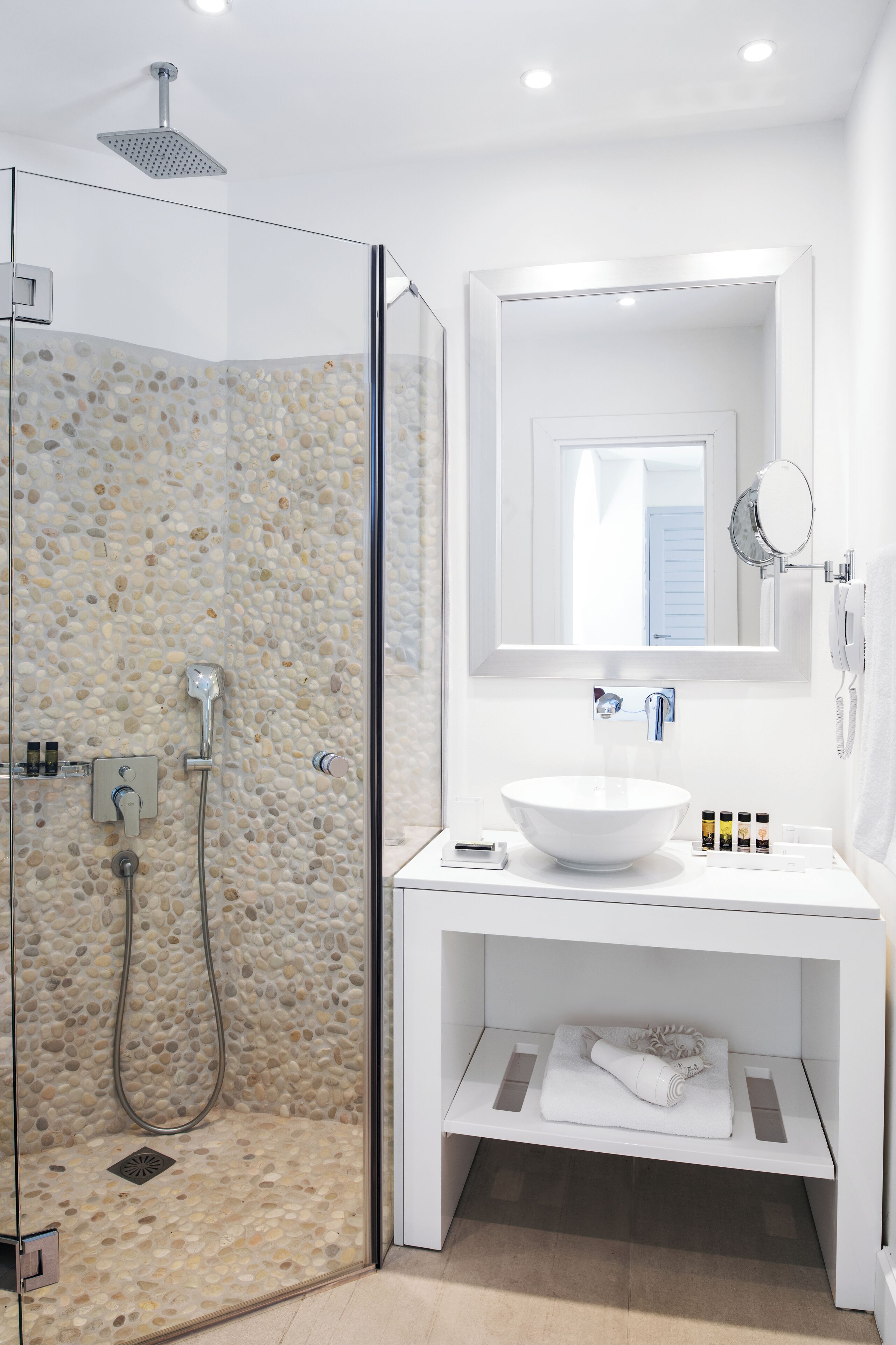 Ein modernes Badezimmer mit einer Duschkabine, einem weißen Waschbecken und einem Spiegel darüber.