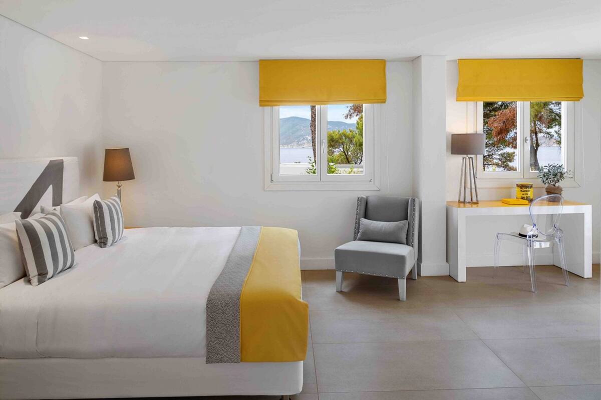 A hotel room with a bed, a desk, a chair, and a view of the outdoors.