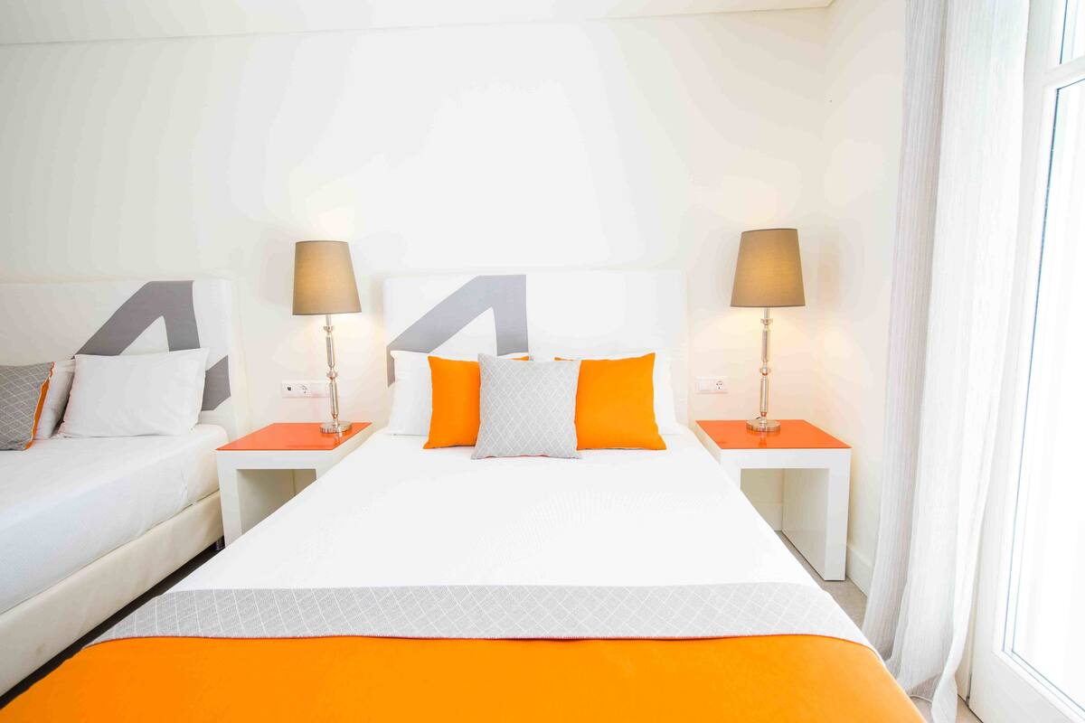 A hotel room with a large bed, two bedside tables, and two lamps.