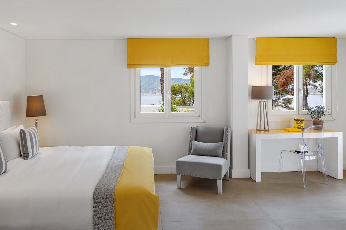 Una camera d'albergo con un letto, una scrivania, una sedia e una finestra vista all'esterno.