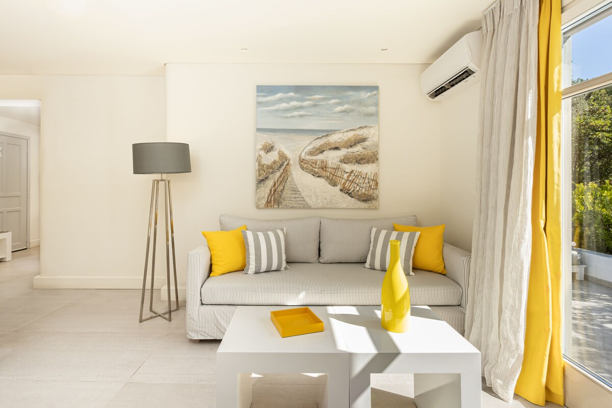 Un soggiorno moderno con un divano a righe, una lampada da terra e un quadro raffigurante una spiaggia.
