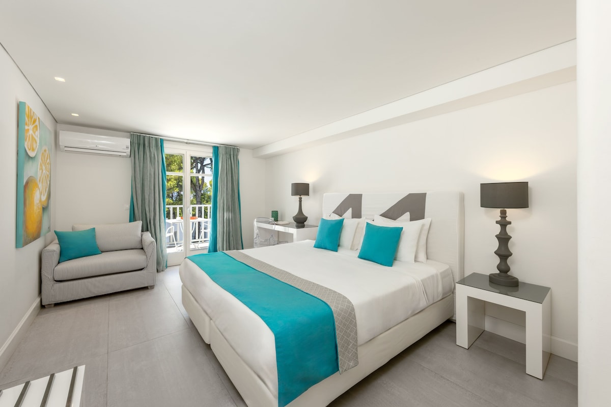 Una habitación de hotel moderna con una cama grande, un sofá, un escritorio y un balcón con cortinas.