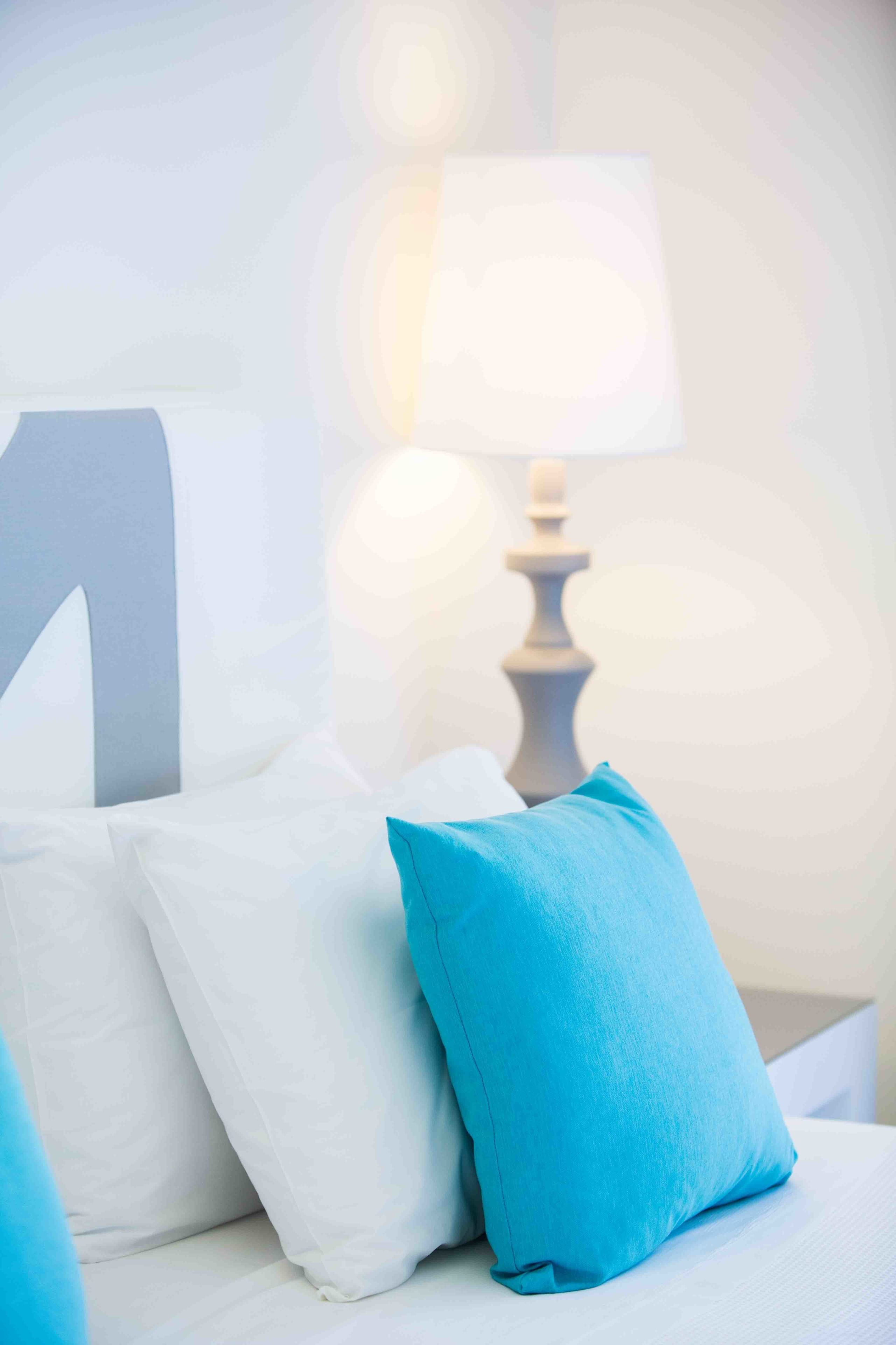 Un lit avec une literie blanche et bleue, une lampe et une grande lettre « N » sur le mur.