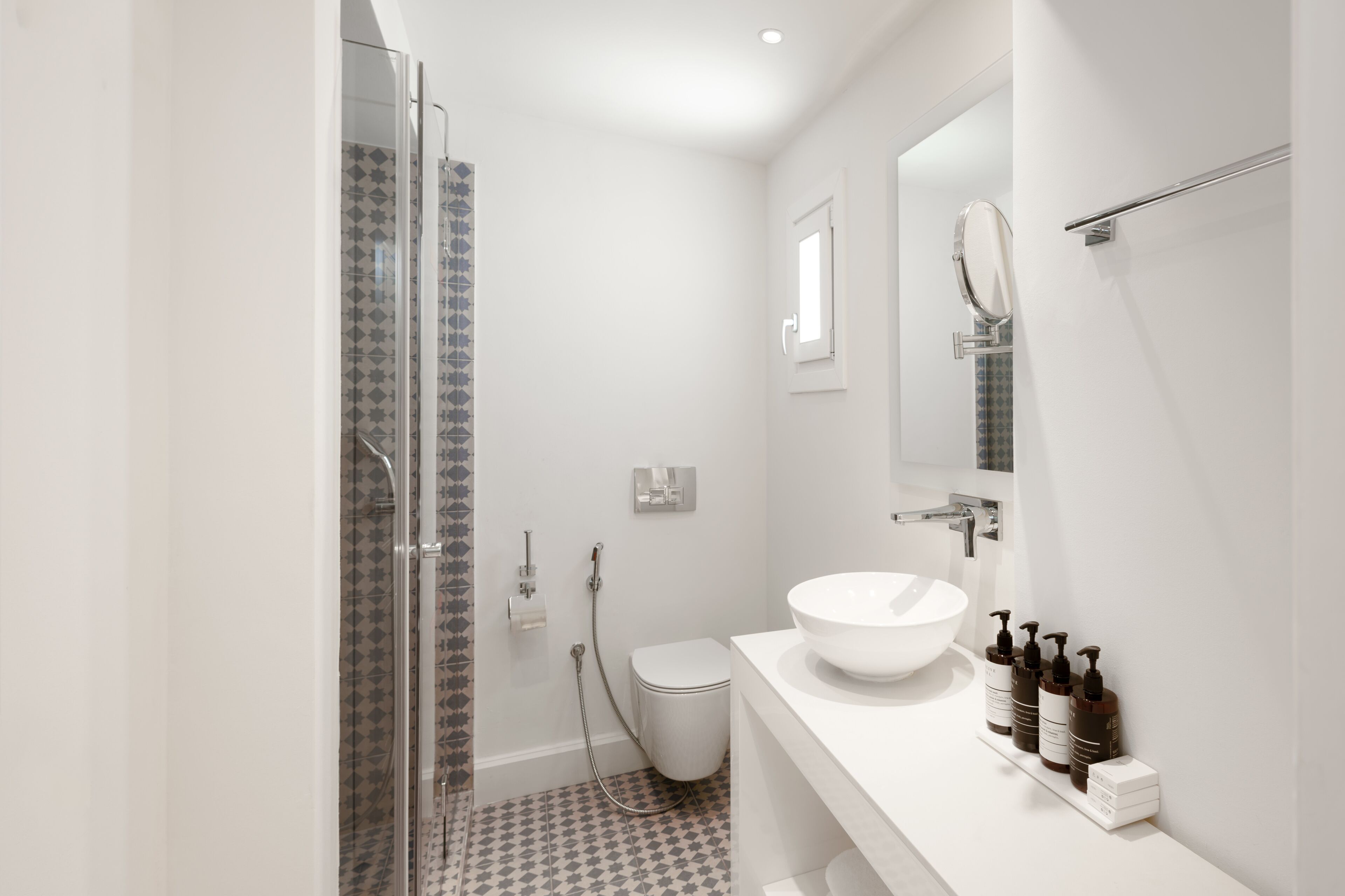 Un baño moderno con cabina de ducha de vidrio, un lavabo blanco y un inodoro.