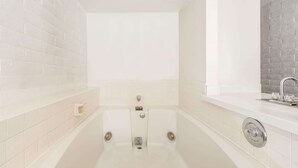 Une salle de bain moderne avec une grande baignoire, un lavabo séparé et un mur recouvert de carreaux.