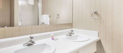 Une salle de bain moderne avec deux lavabos, un miroir et une douche.