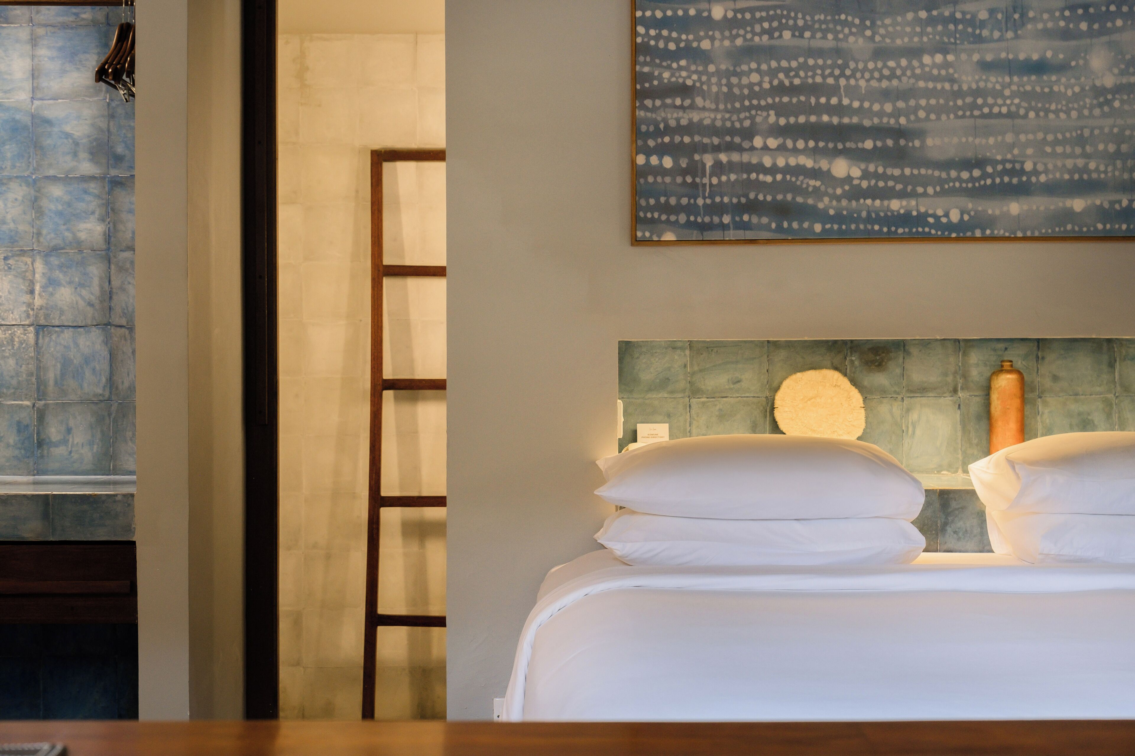 Une chambre d’hôtel avec un lit, un porte-serviettes, un tableau et un mur recouvert de carreaux.