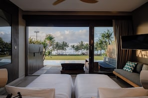 Habitación de hotel con dos camas, televisión, sofá y vista a la playa.