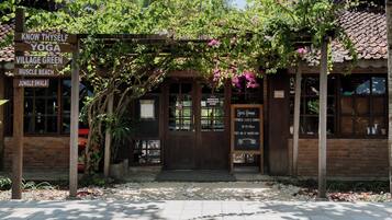 A building with a wooden entrance, signs for yoga, village green, muscle beach, and jungle shala.