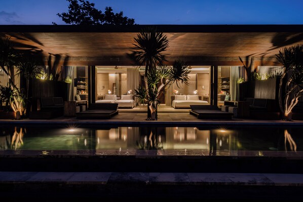 A modern hotel with a pool, two bedrooms, and a dining area.